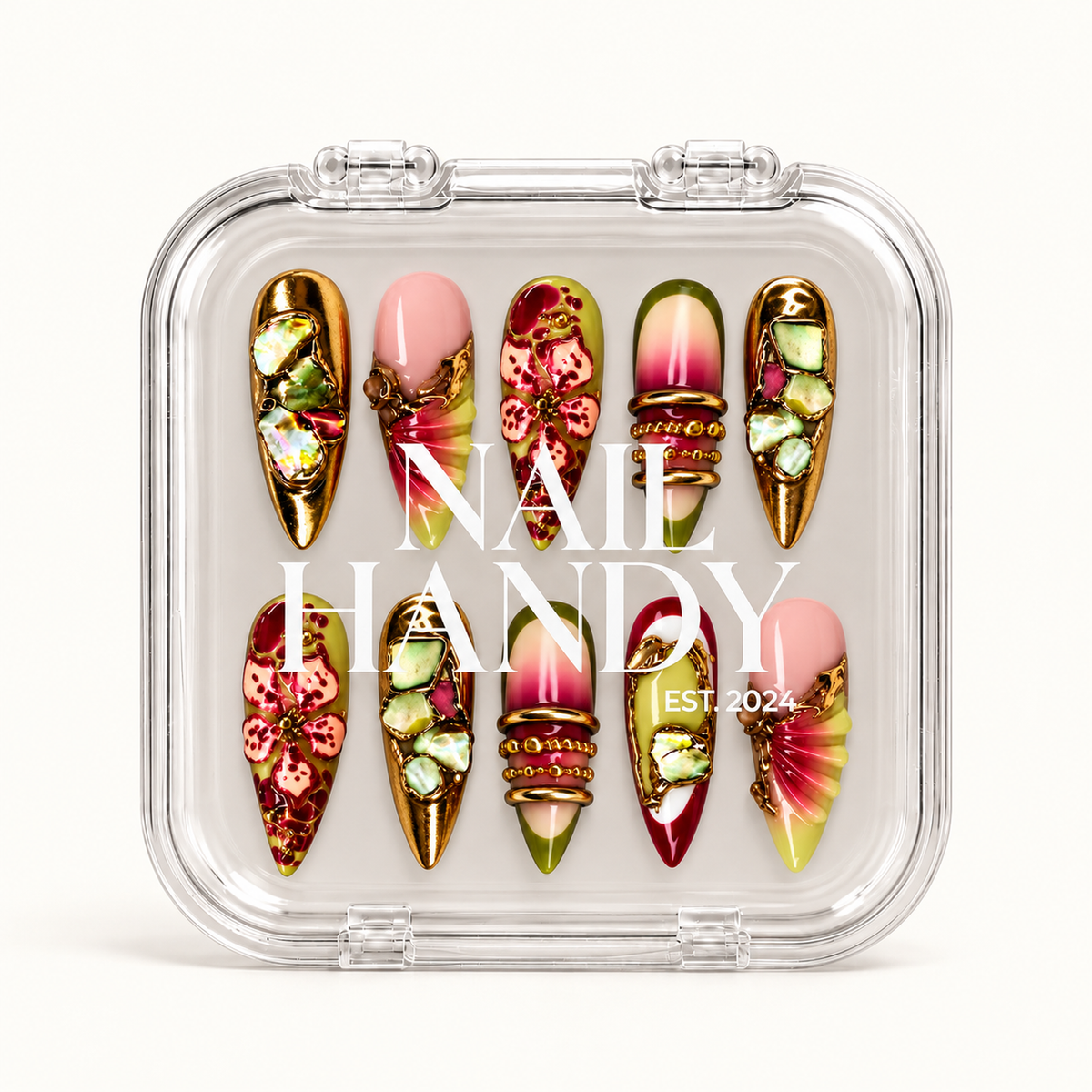 Closed clear case displaying ten ornate pink, olive, and gold nails beneath white Nail Handy lettering.