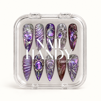 Closed clear Nail Handy case displaying ten purple and silver nails beneath white branding on a light background.