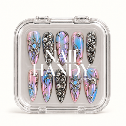 Closed clear Nail Handy case displaying ten iridescent pink, lavender, and blue nails with reflective silver ornamentation beneath white lid lettering.