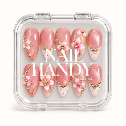 Closed clear Nail Handy case displaying ten blush pink floral nails beneath white branding, with gold-colored accents and dotted ivory tips.