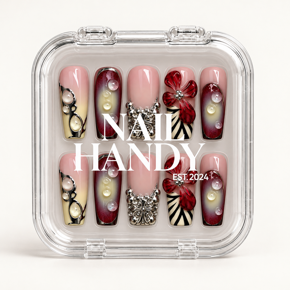 Closed clear Nail Handy case displaying ten coordinated floral and ornamental nails beneath white branding on a light background.