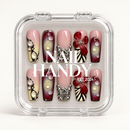 Closed clear Nail Handy case displaying ten coordinated floral and ornamental nails beneath white branding on a light background.