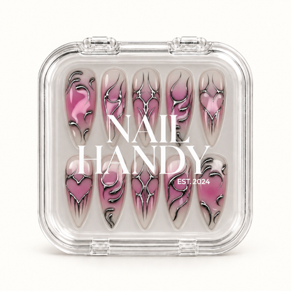 Closed clear case with white Nail Handy lettering displaying ten coordinated mauve and greige nails with silver chrome-look heart and pointed designs.