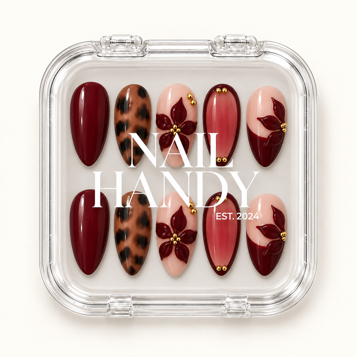 Closed clear case displaying ten burgundy, leopard-print, and blush floral nails beneath white Nail Handy lettering.