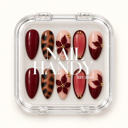 Closed clear case displaying ten burgundy, leopard-print, and blush floral nails beneath white Nail Handy lettering.