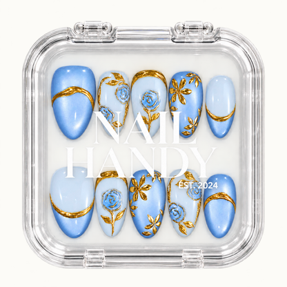 Closed clear Nail Handy case displaying ten blue and pale blue nails with gold botanical details, arranged in two rows beneath white branding.