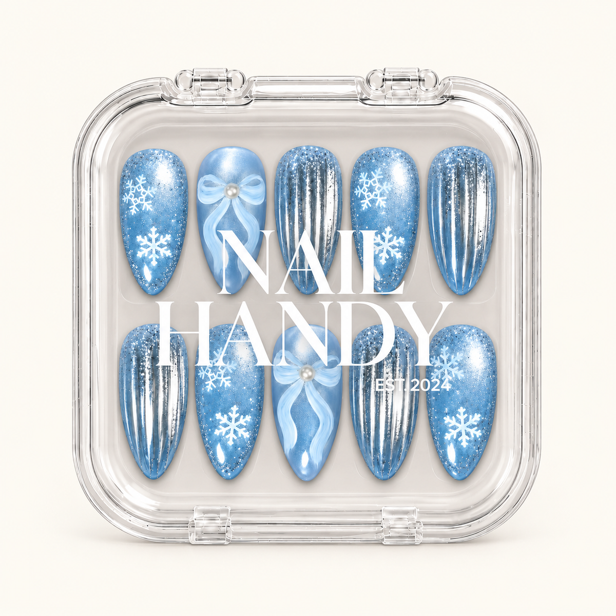Closed clear case displaying ten icy blue snowflake, bow, and silver-striped nails beneath white lettering on the lid.