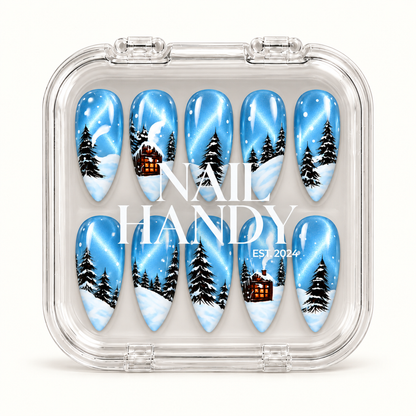 Closed clear case containing ten blue winter woodland nails, with white Nail Handy branding across the lid on a light background.