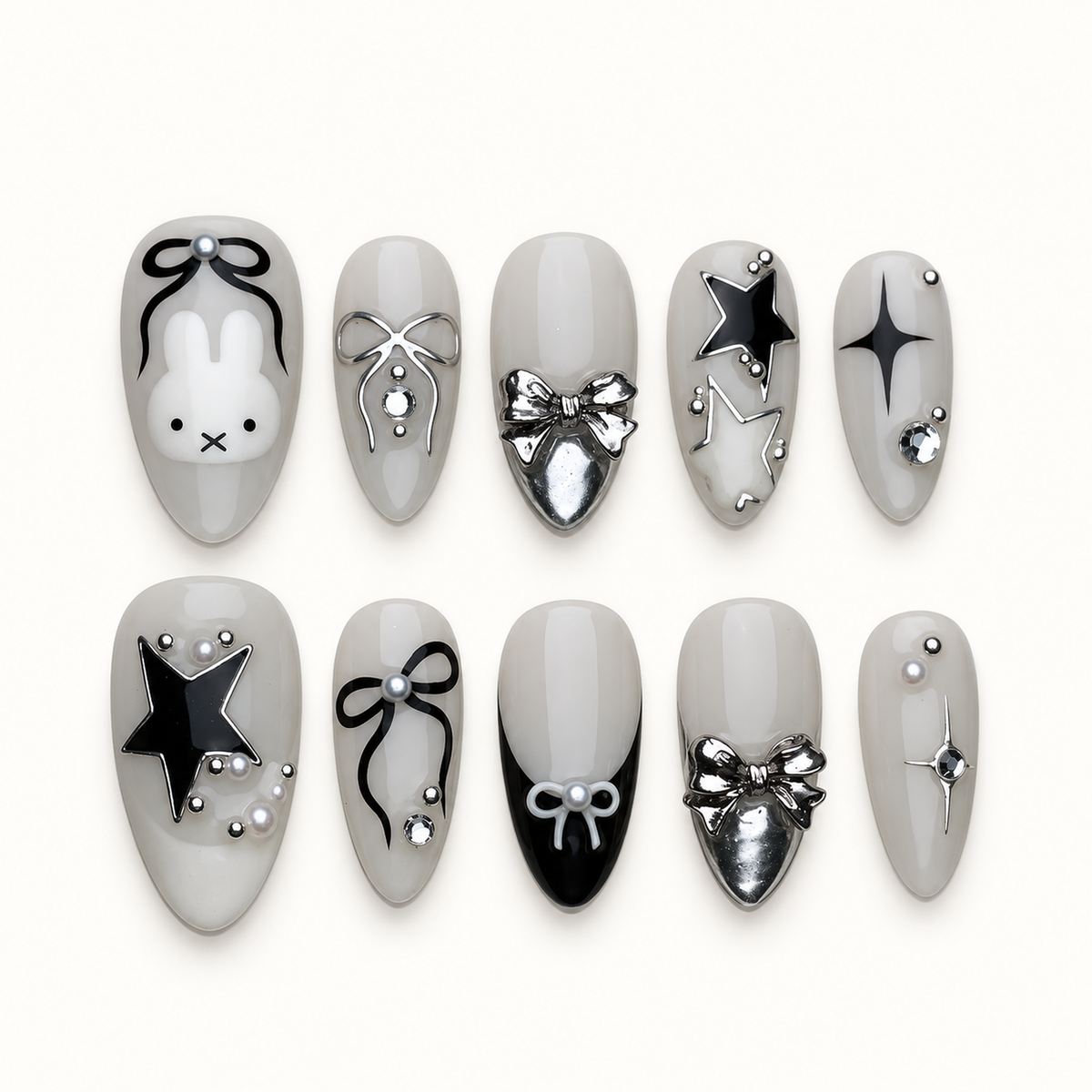 Ten glossy greige press-on nails arranged in two rows, featuring a bunny face, bows, stars, silver accents, and a black tip.