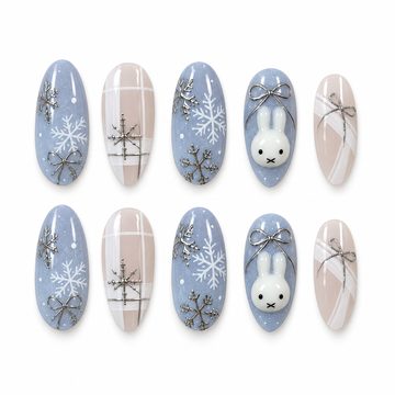 Ten Snowbound Bunny nails arranged in two rows, showing blue snowflake and bunny designs beside nude plaid and bow accents.