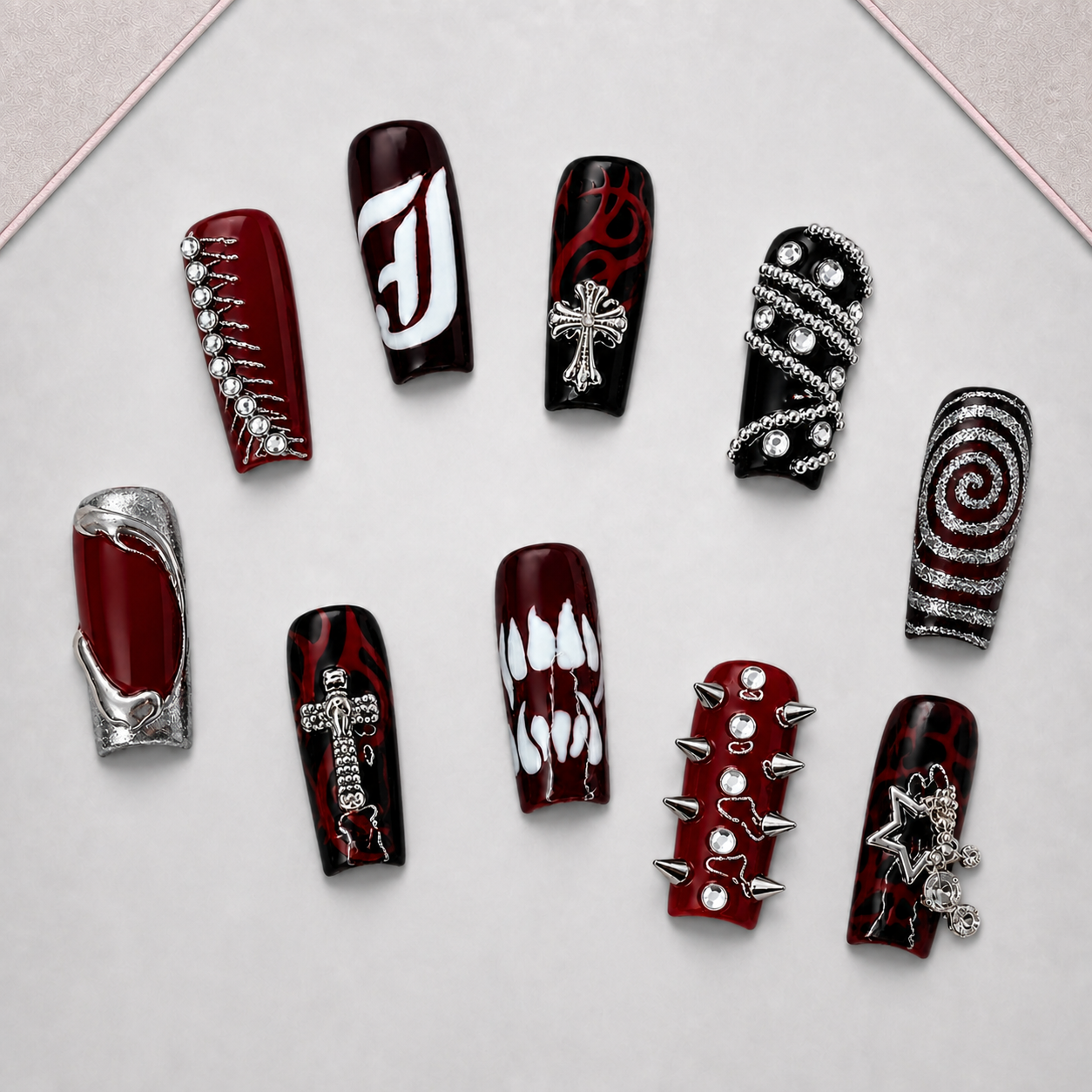 Crimson Relic press-on nail set displayed on an approved walnut tray, showing burgundy and black gothic-inspired designs with silver dimensional accents.