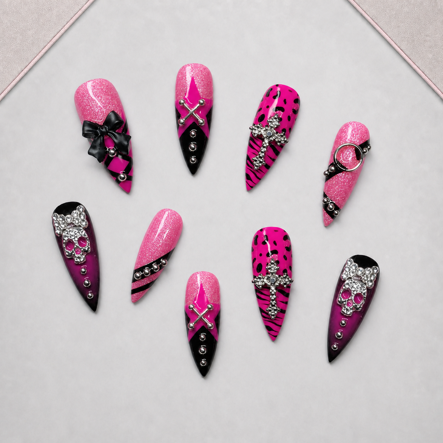 Pink Noir Charm press-on nail set arranged on an approved display tray, showing mixed pink-and-black embellished designs.