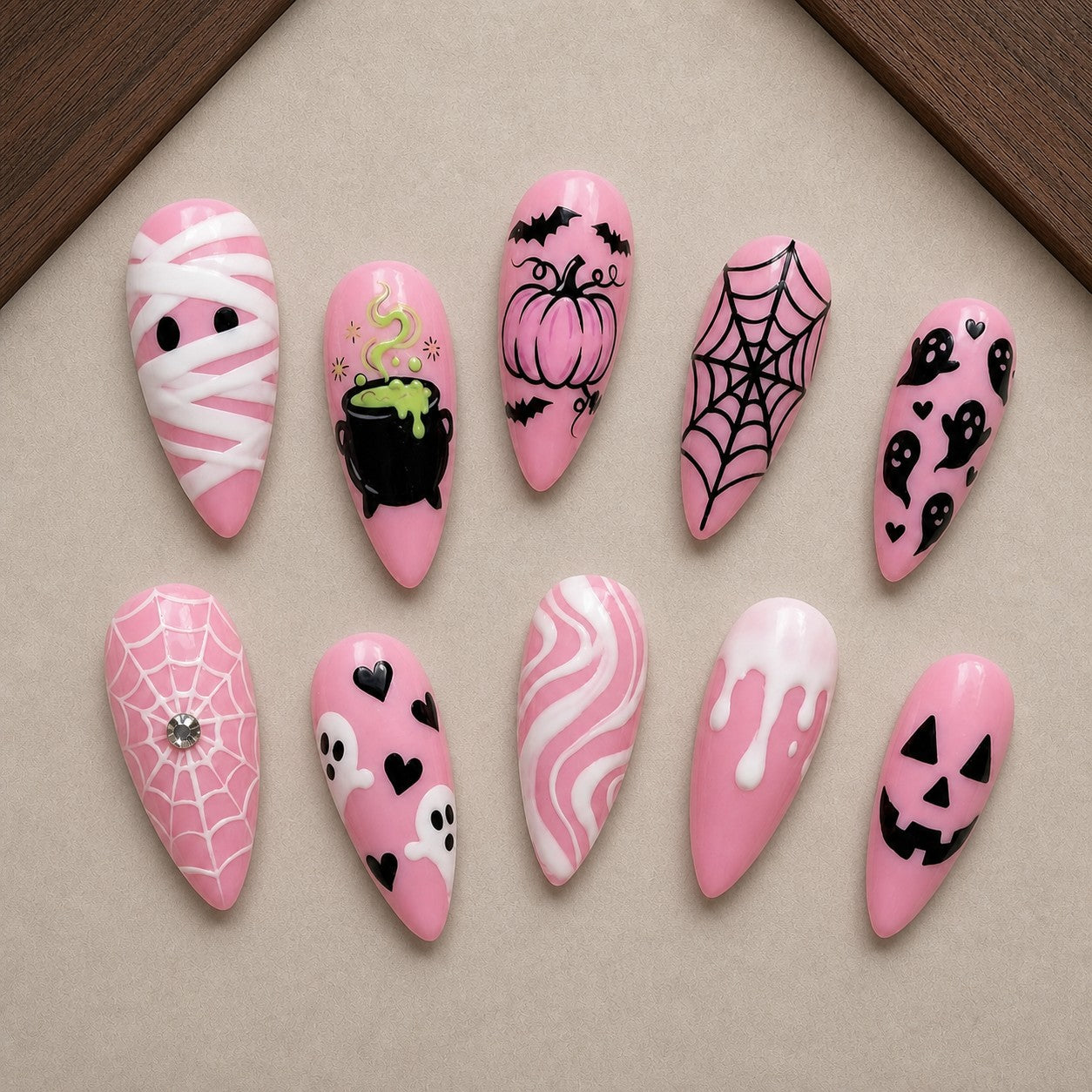 Pink Potion Halloween press-on nail set displayed in a walnut tray — almond shape